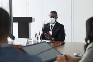 Homme professionnel discute autour d'une table en entreprise avec un masque chirurgical