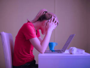 Une femme se prend la tête devant un ordinateur