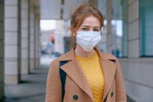 Femme avec un masque chirurgicale devant une banque